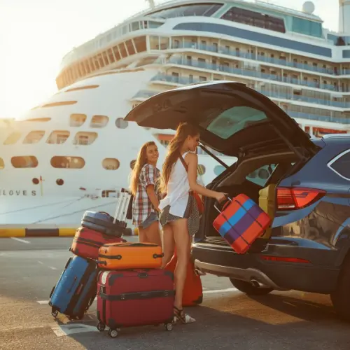 Happy travelers loading luggage into a car near a cruise ship, illustrating pre- and post-cruise land tour extensions arranged by Travel Tranquility.