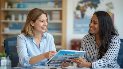 A friendly personal travel advisor reviewing vacation plans and brochures with a smiling client, demonstrating expert planning assistance.