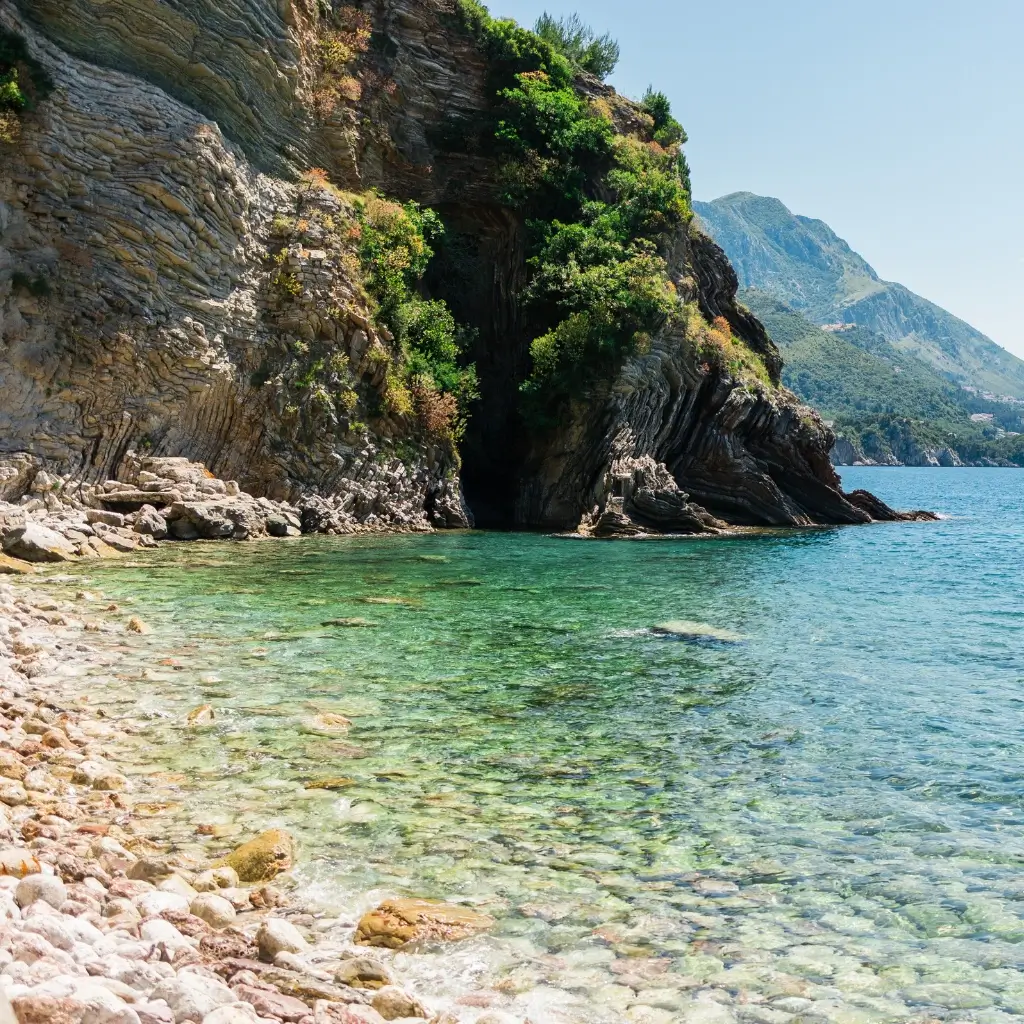 A hidden rocky cove with crystal clear turquoise water along the sunny Budva coast.