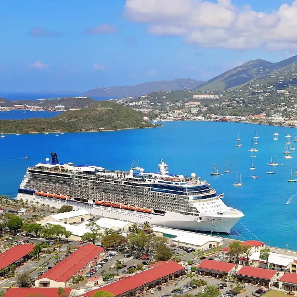 A massive cruise ship docked in a beautiful tropical port in the Caribbean