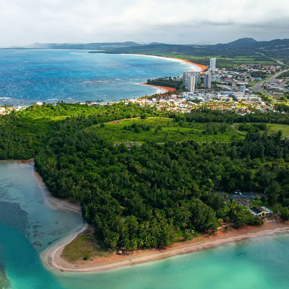 Aerial view of a lush green tropical peninsula and beautiful blue water along the Puerto Rico coastline.