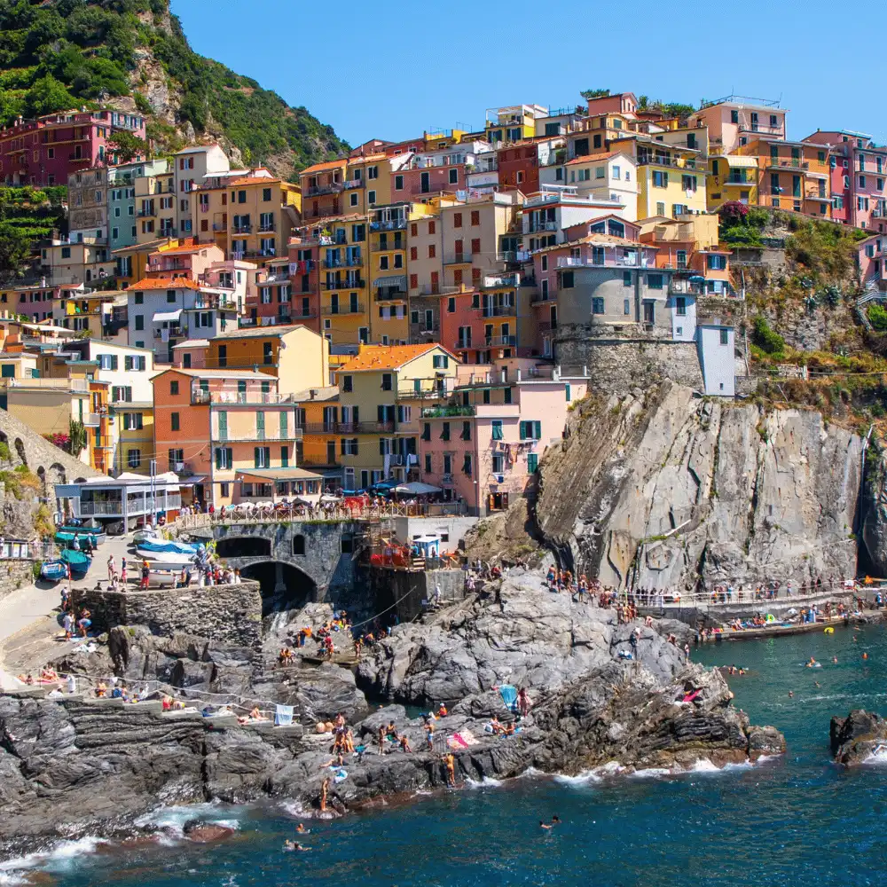 Colorful stacked houses built into the rugged cliffs of Cinque Terre overlooking the Mediterranean Sea in Italy.