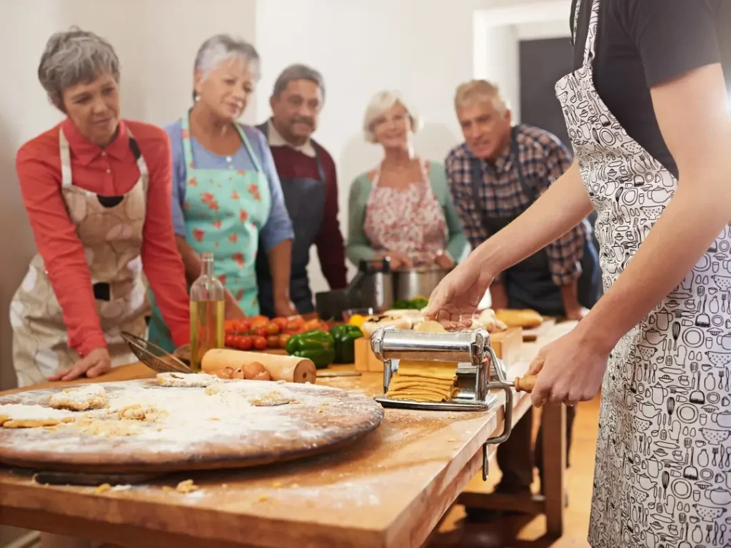 A group of travelers watching a chef make fresh pasta during an authentic cooking class in Italy.