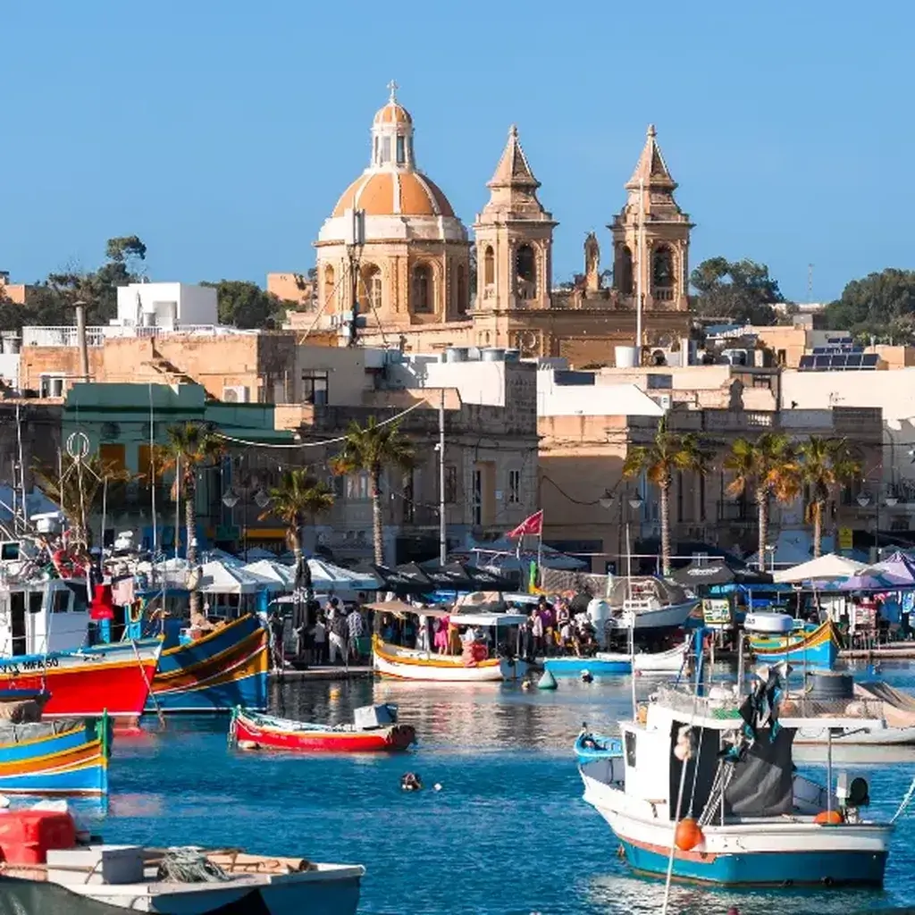 Traditional colorful Luzzu boats floating on the bright turquoise waters of Marsaxlokk, Malta