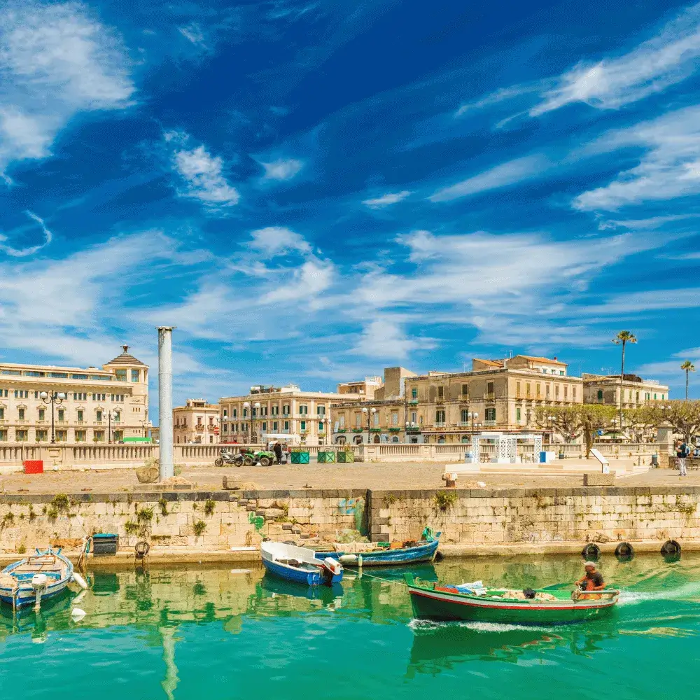 Historic waterfront architecture and small boats in the vibrant harbor of Syracuse, Sicily.