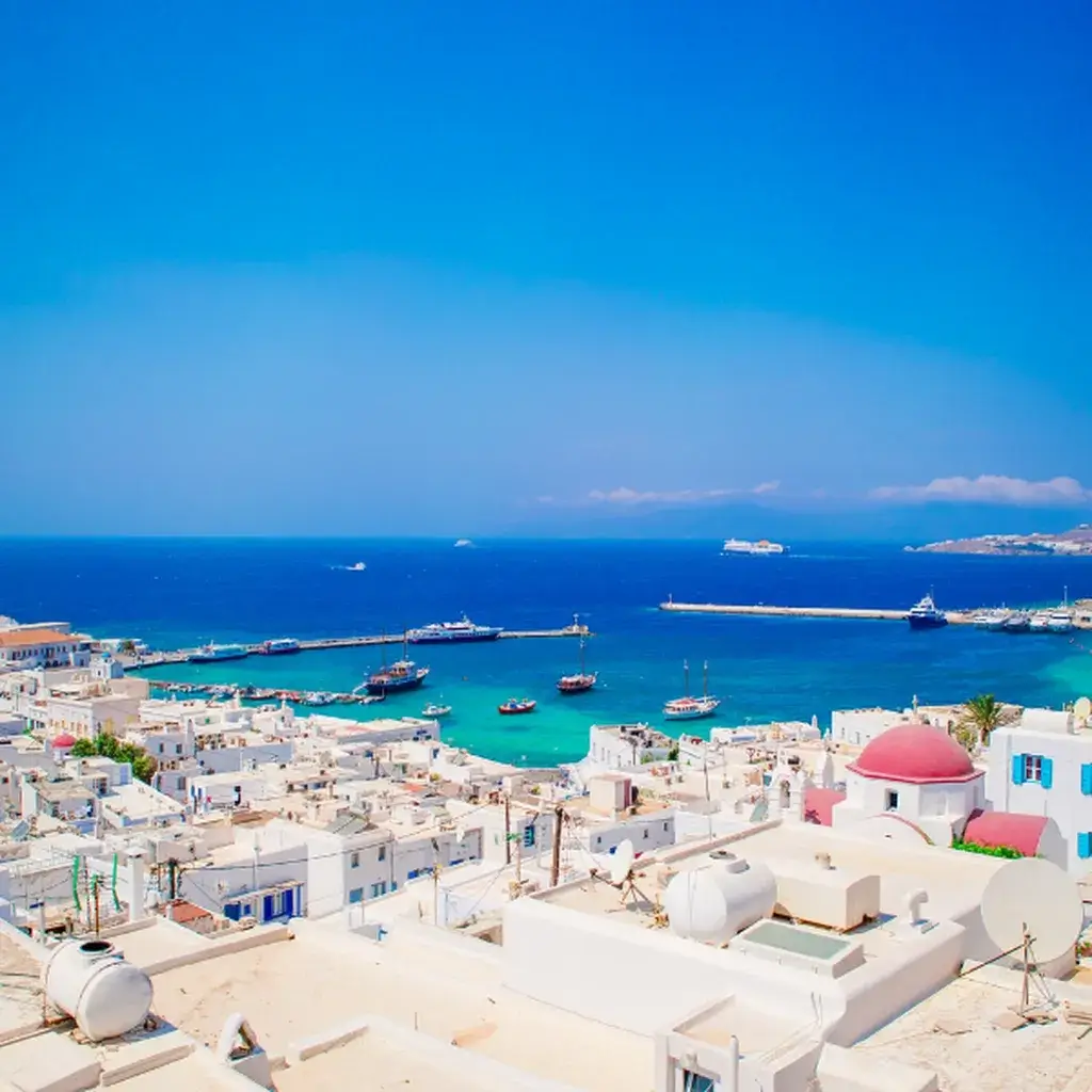 A sun-drenched rooftop view over the whitewashed buildings and blue sea of Mykonos, Greece