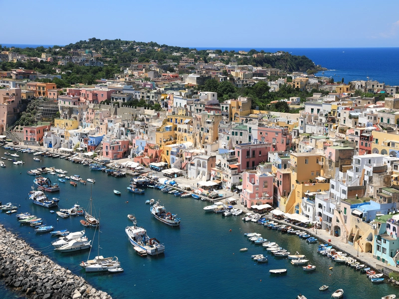 Colorful pastel fisherman houses clustered along the waterfront harbor of Procida Island in Italy.